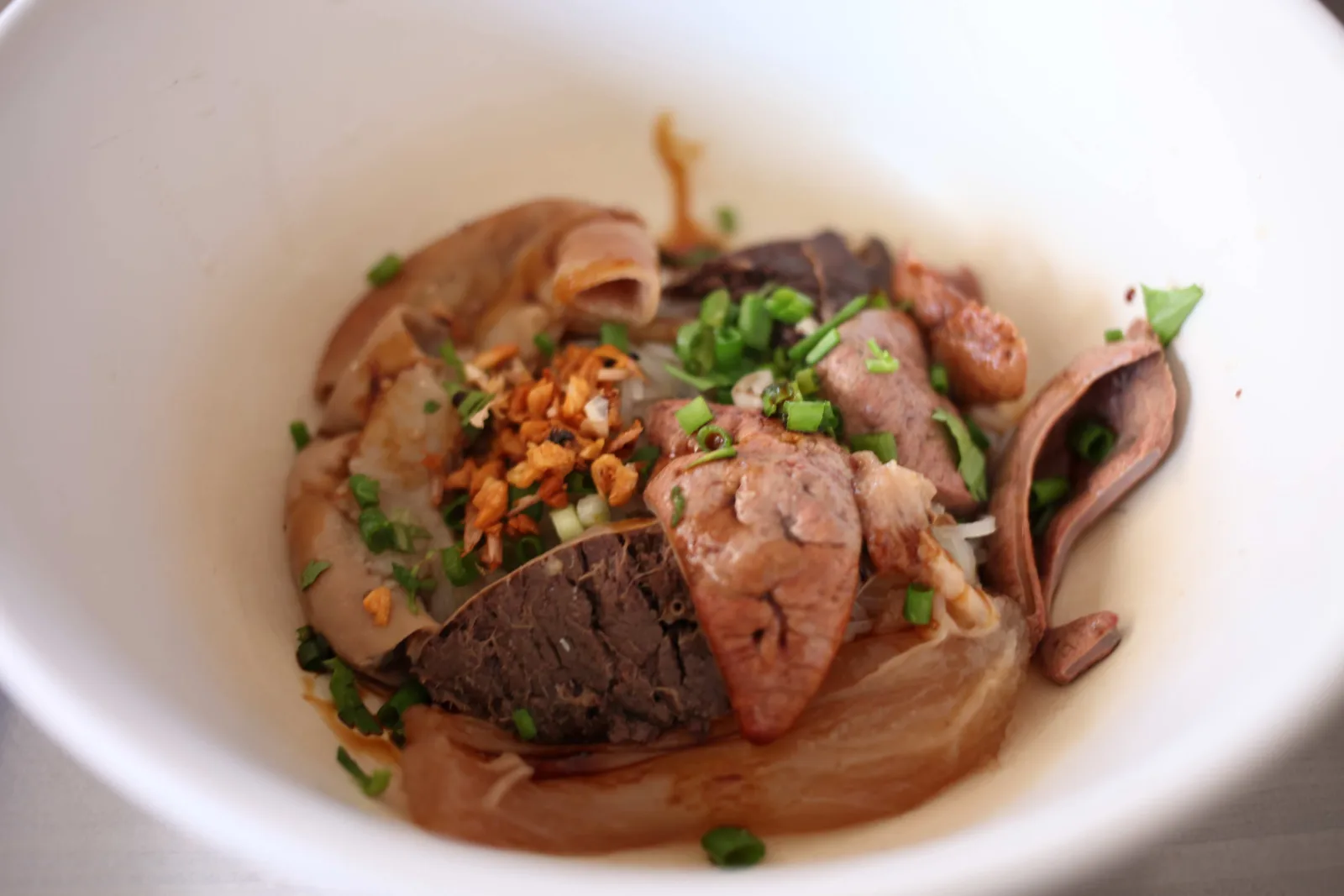 ก๋วยเตี๋ยวเนื้อแห้งในชามขาว โรยกระเทียมเจียวและต้นหอม
