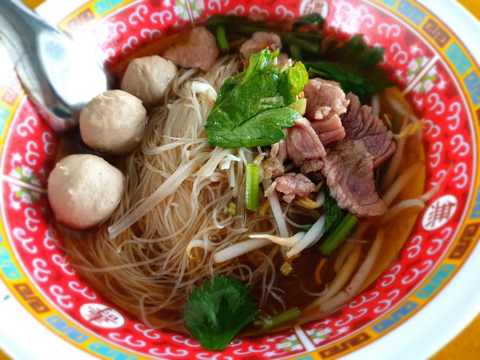 ก๋วยเตี๋ยวเนื้อน้ำใสเส้นหมี่ในชามลายมังกร มีเนื้อสดและลูกชิ้น